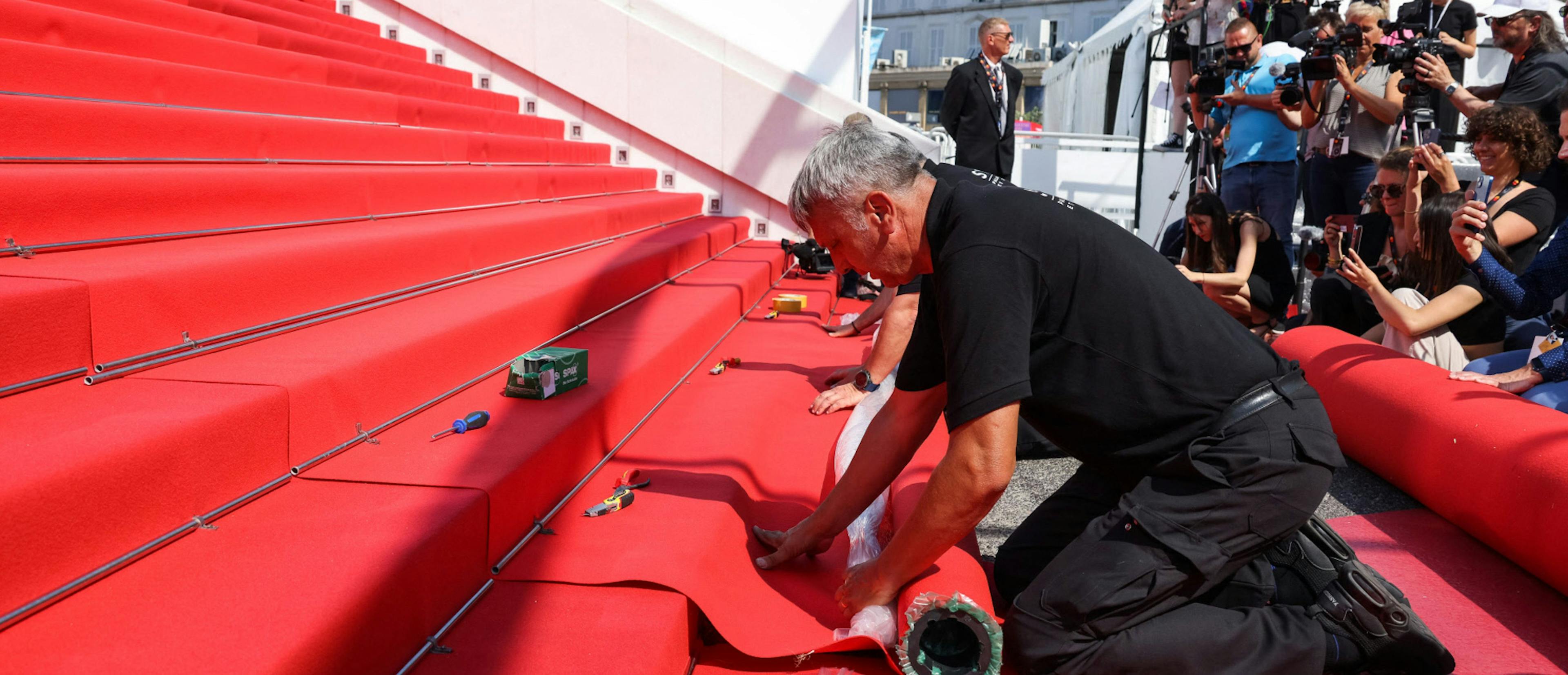 Un operario del Festival de Cannes coloca la alfombra roja de la escalinata en la edición 75 de la muestra