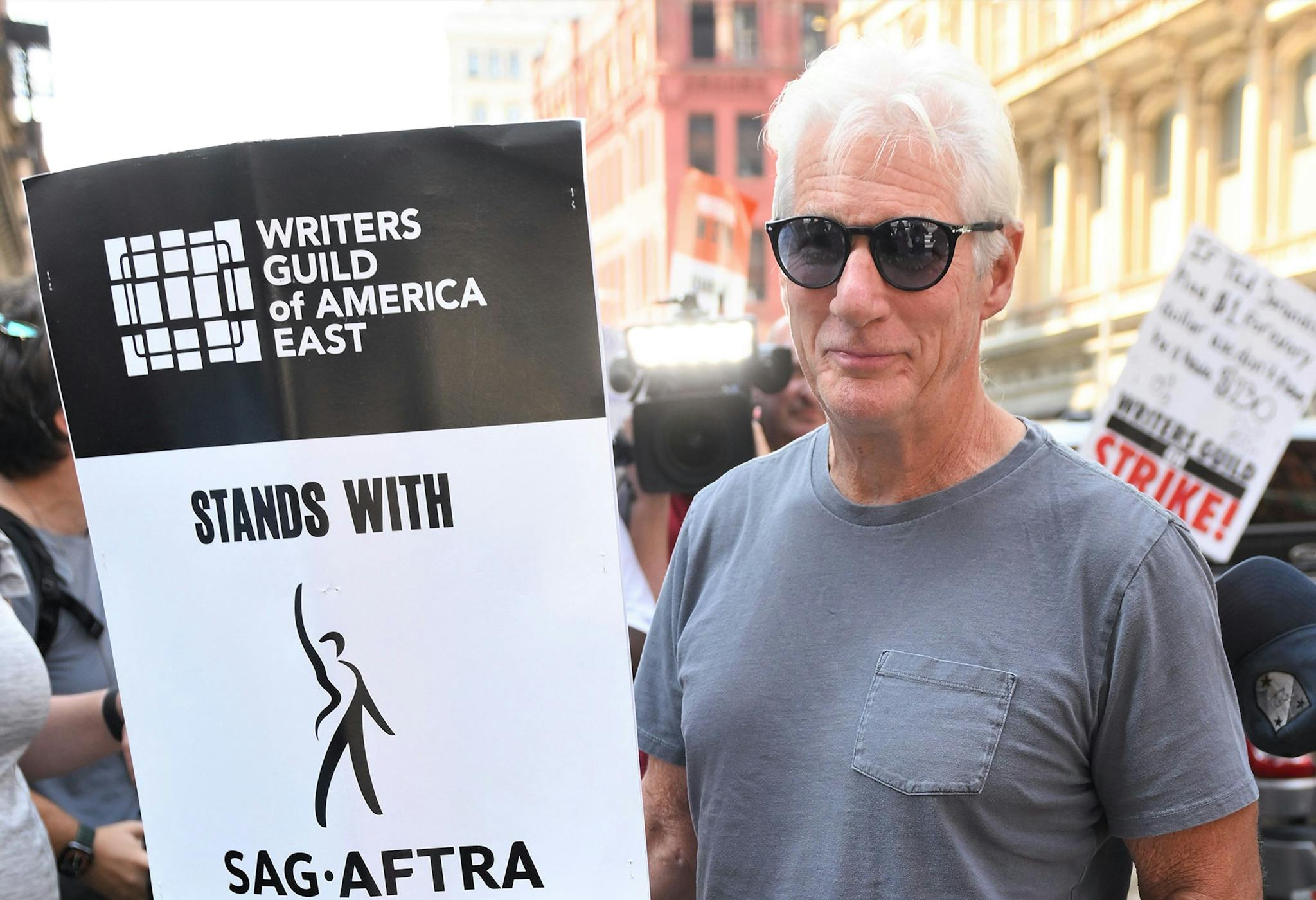 Richard Gere, en un piquete en Nueva York durante la huelga de actores y con un cartel de apoyo a sus compañeros guionistas