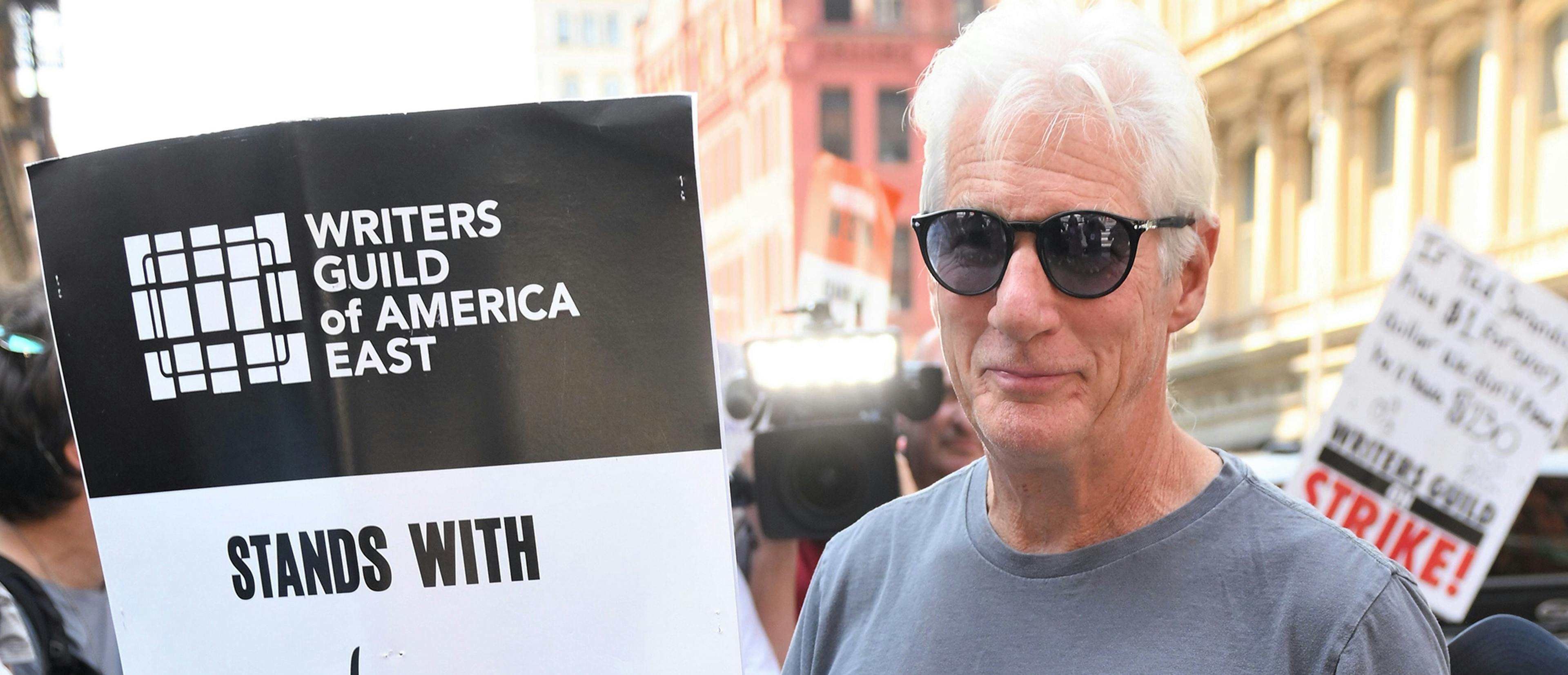 Richard Gere, en un piquete en Nueva York durante la huelga de actores y con un cartel de apoyo a sus compañeros guionistas