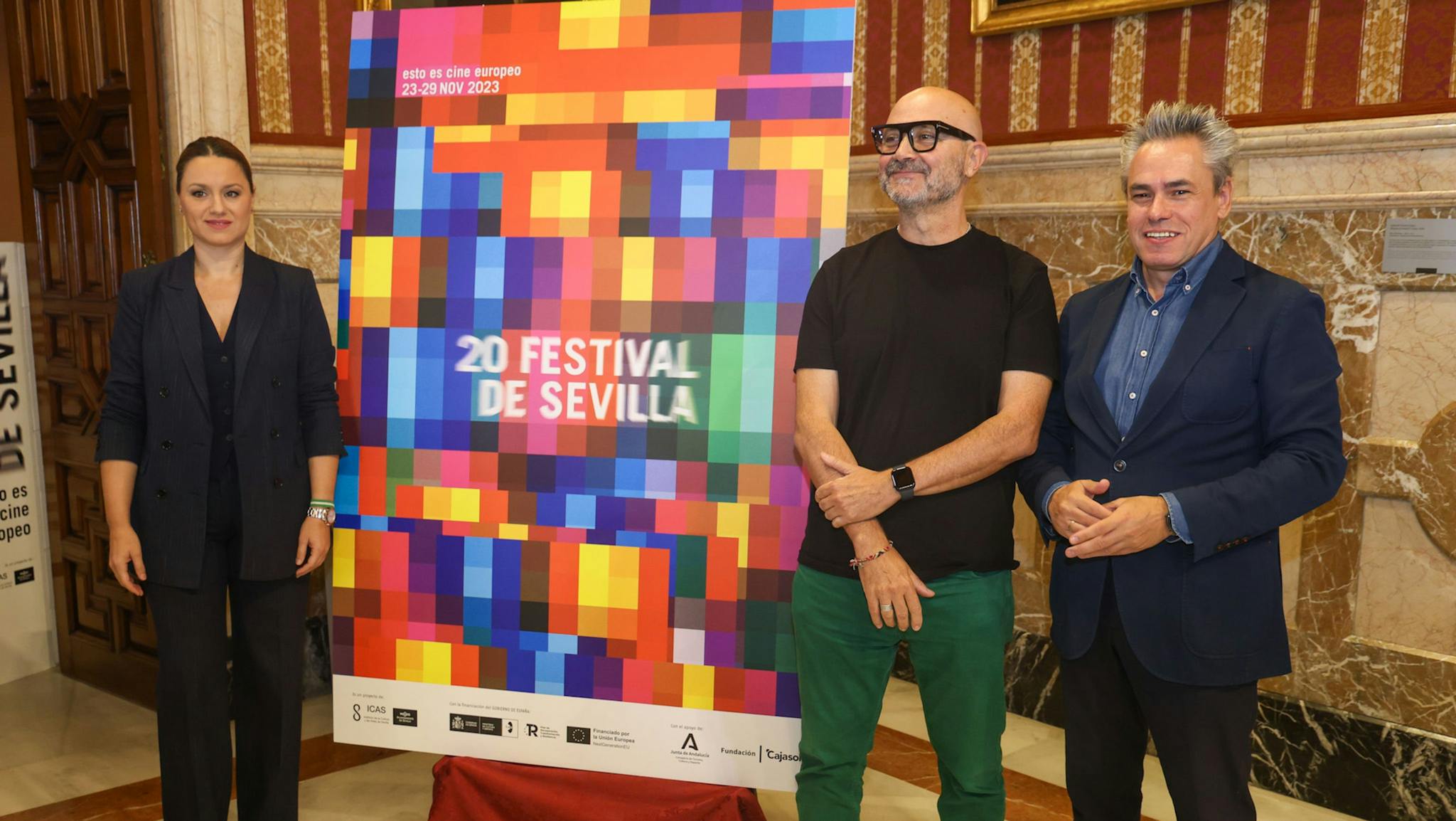 El coordinador del Festival de Sevilla, Manuel Cristóbal (d), posa junto al cartel de la edición número 20