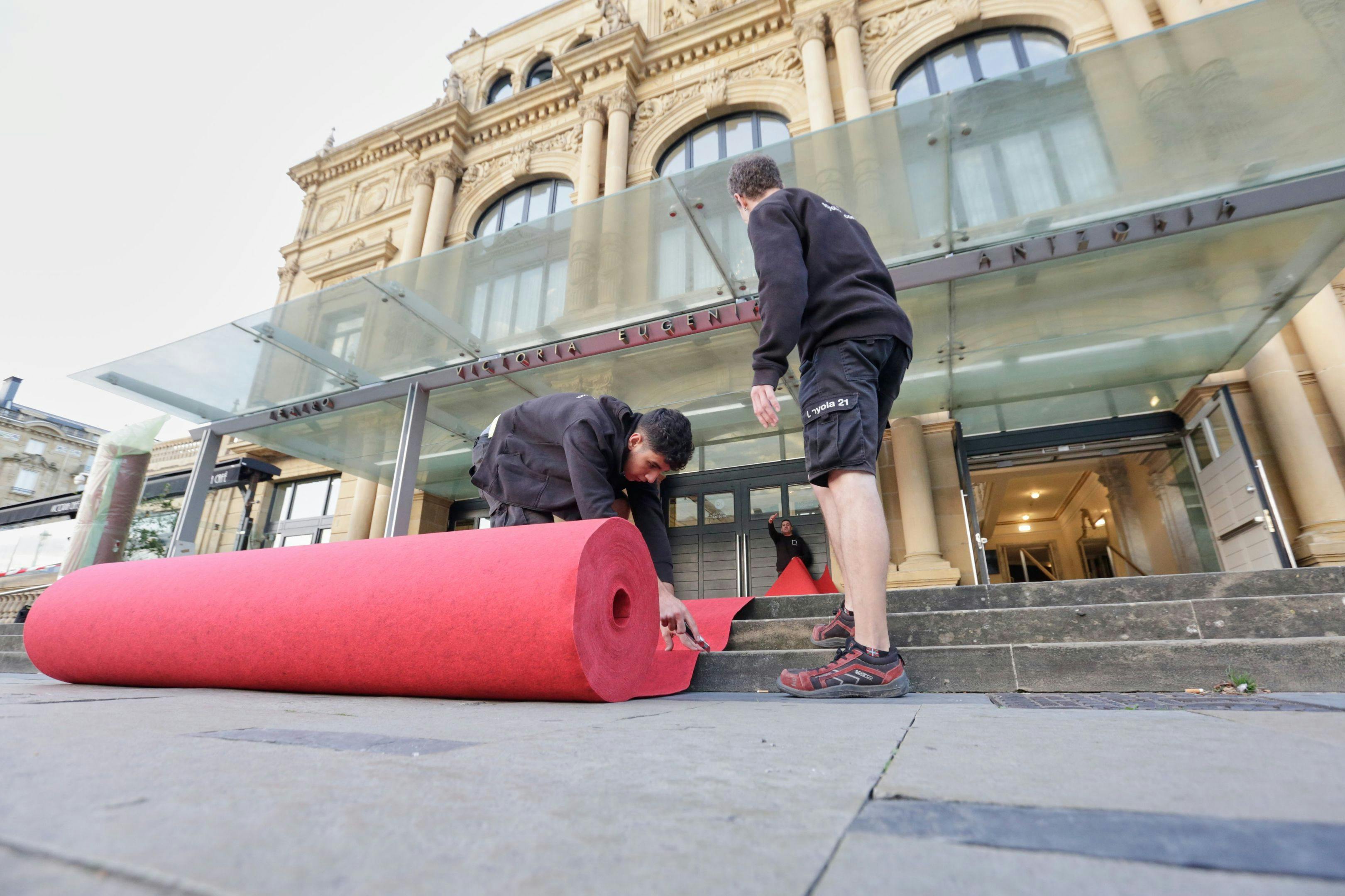 Dos operarios del Festival de San Sebastián despliegan la alfombra roja ante el Teatro Victoria Eugenia