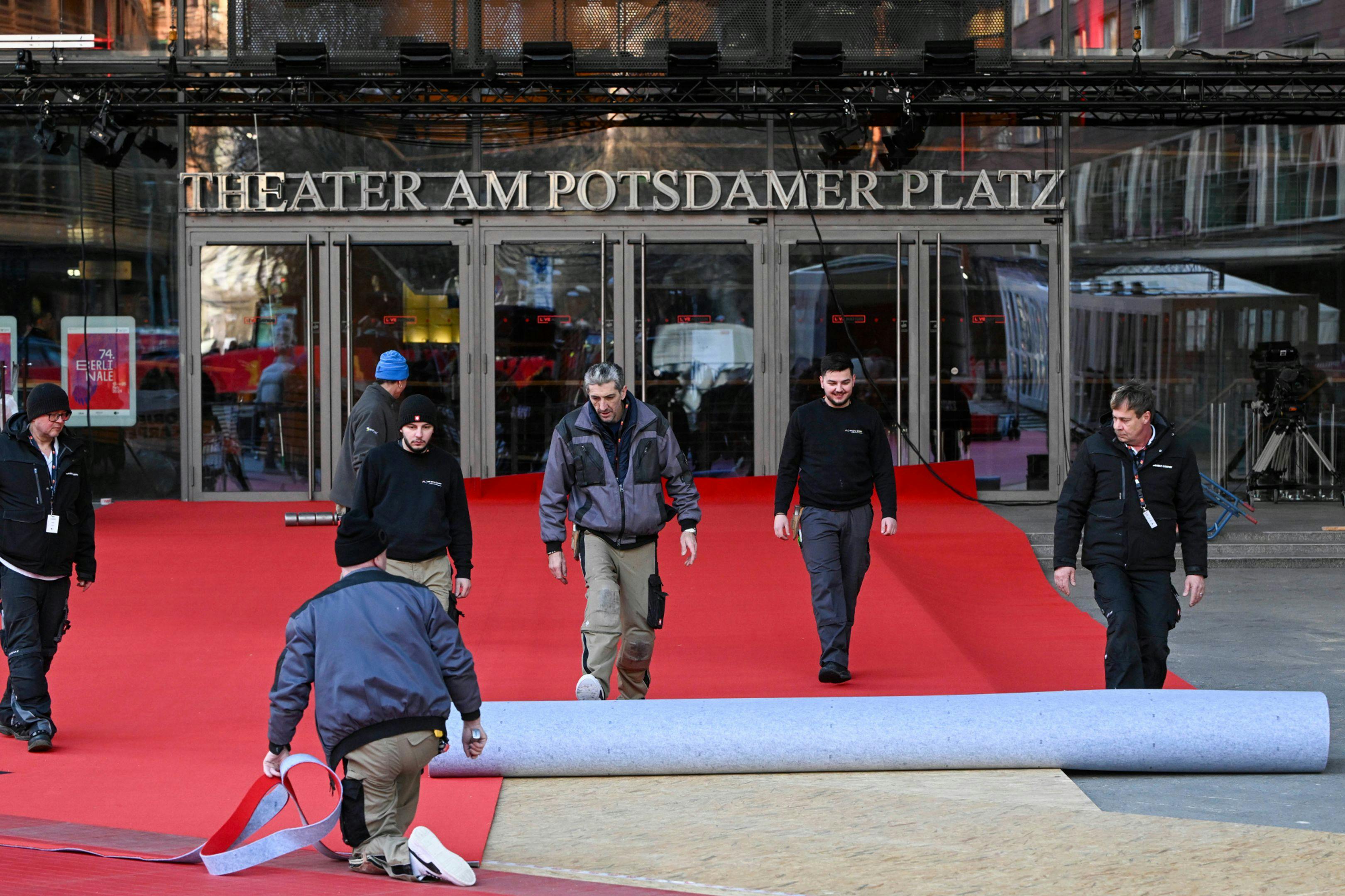 Varios trabajadores del Festival de Berlín despliegan la alfombra roja de la edición de 2024 ante el Berlinale Palast