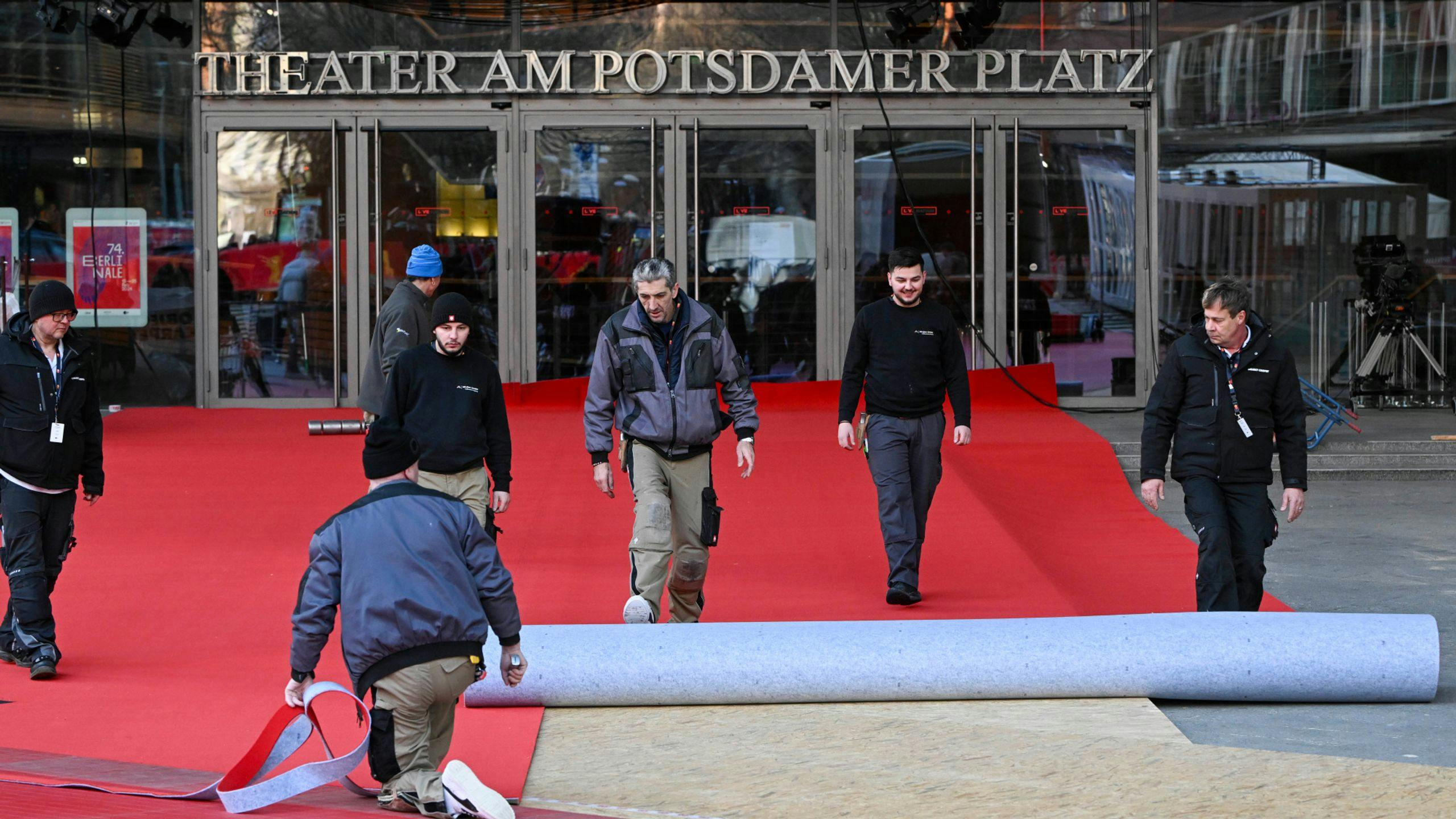 Varios trabajadores del Festival de Berlín despliegan la alfombra roja de la edición de 2024 ante el Berlinale Palast