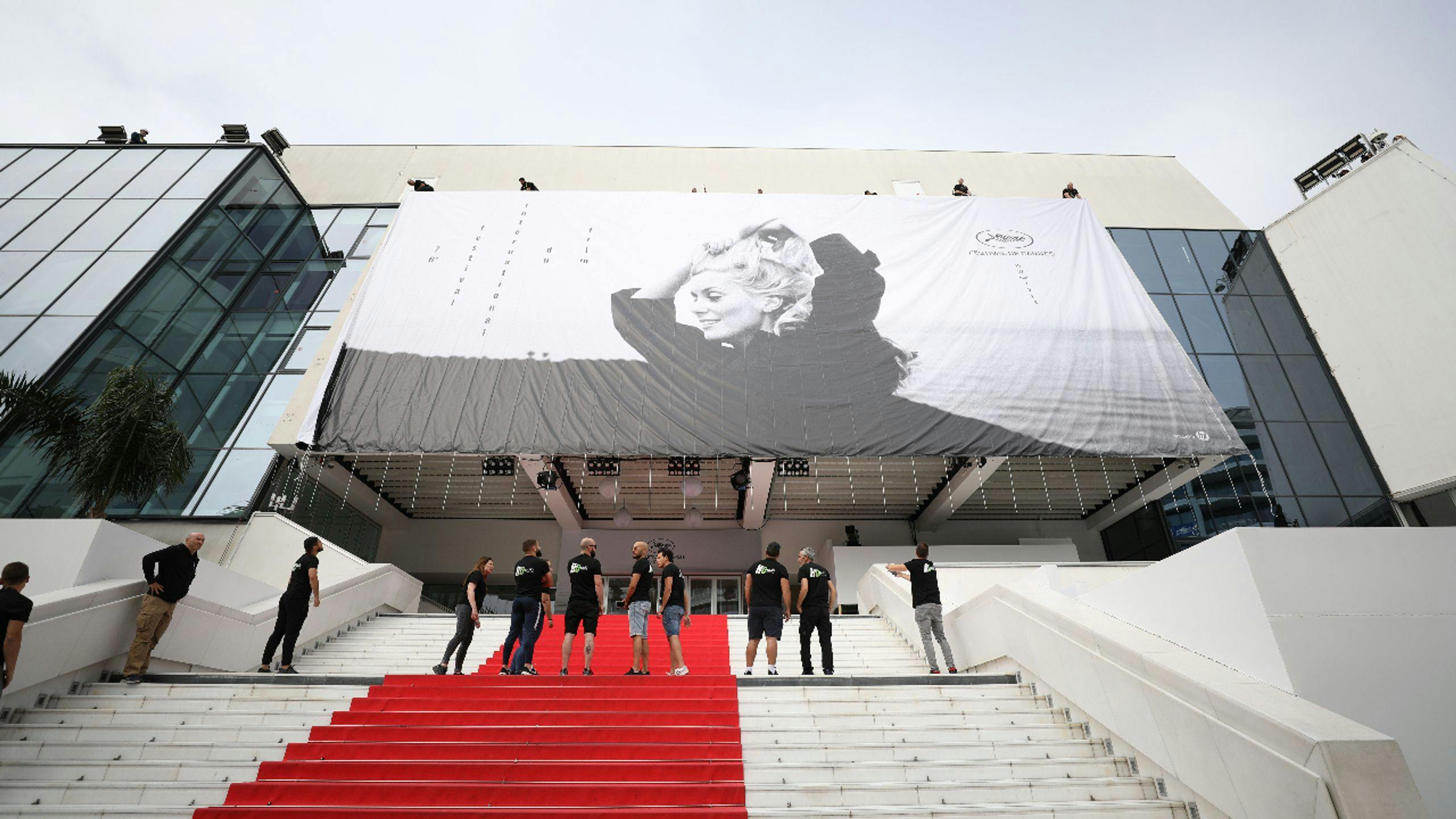 Varios operarios supervisan la colocación de la lona del 76 Festival de Cannes en el Palais des Festivals