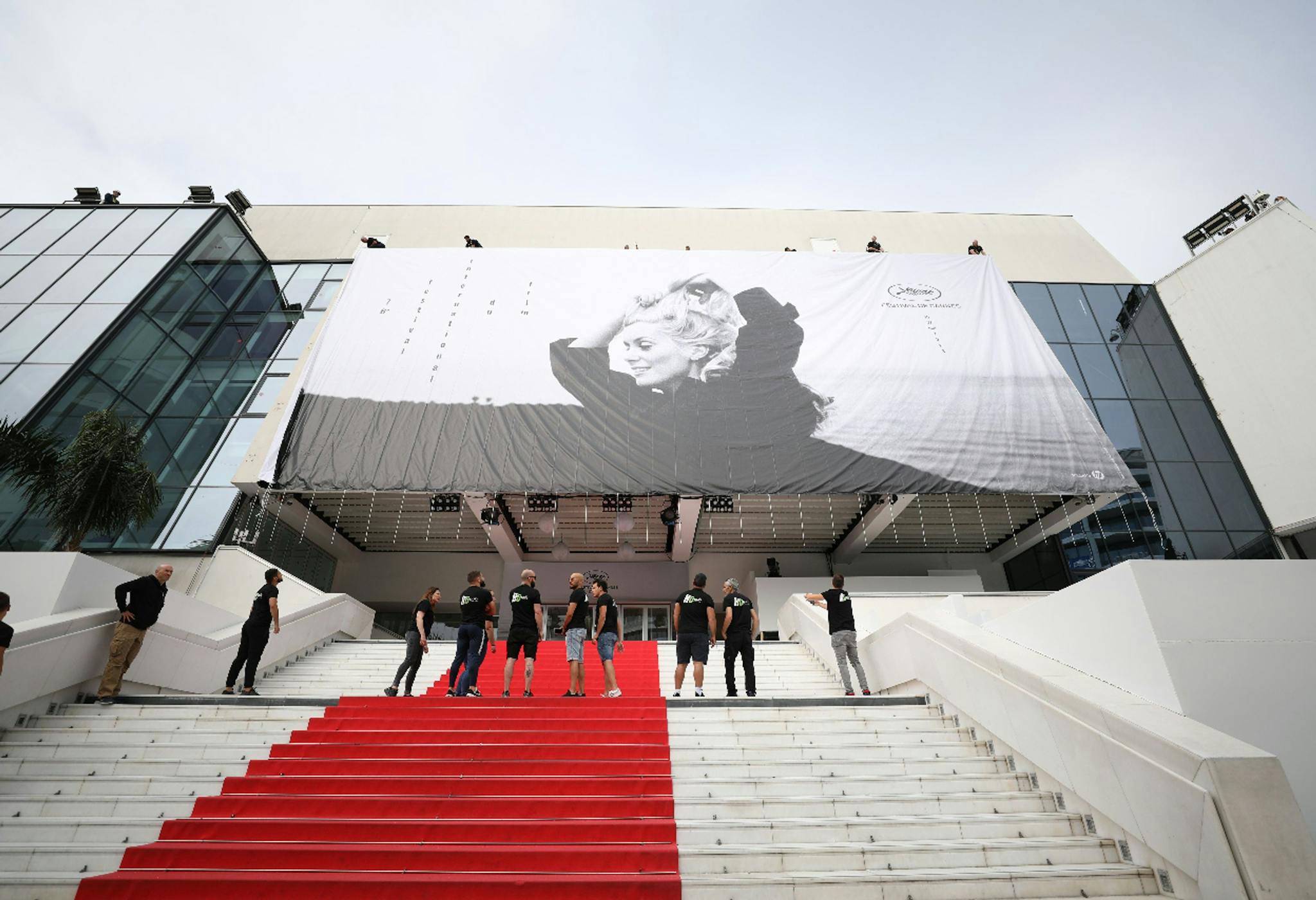 Varios operarios supervisan la colocación de la lona del 76 Festival de Cannes en el Palais des Festivals