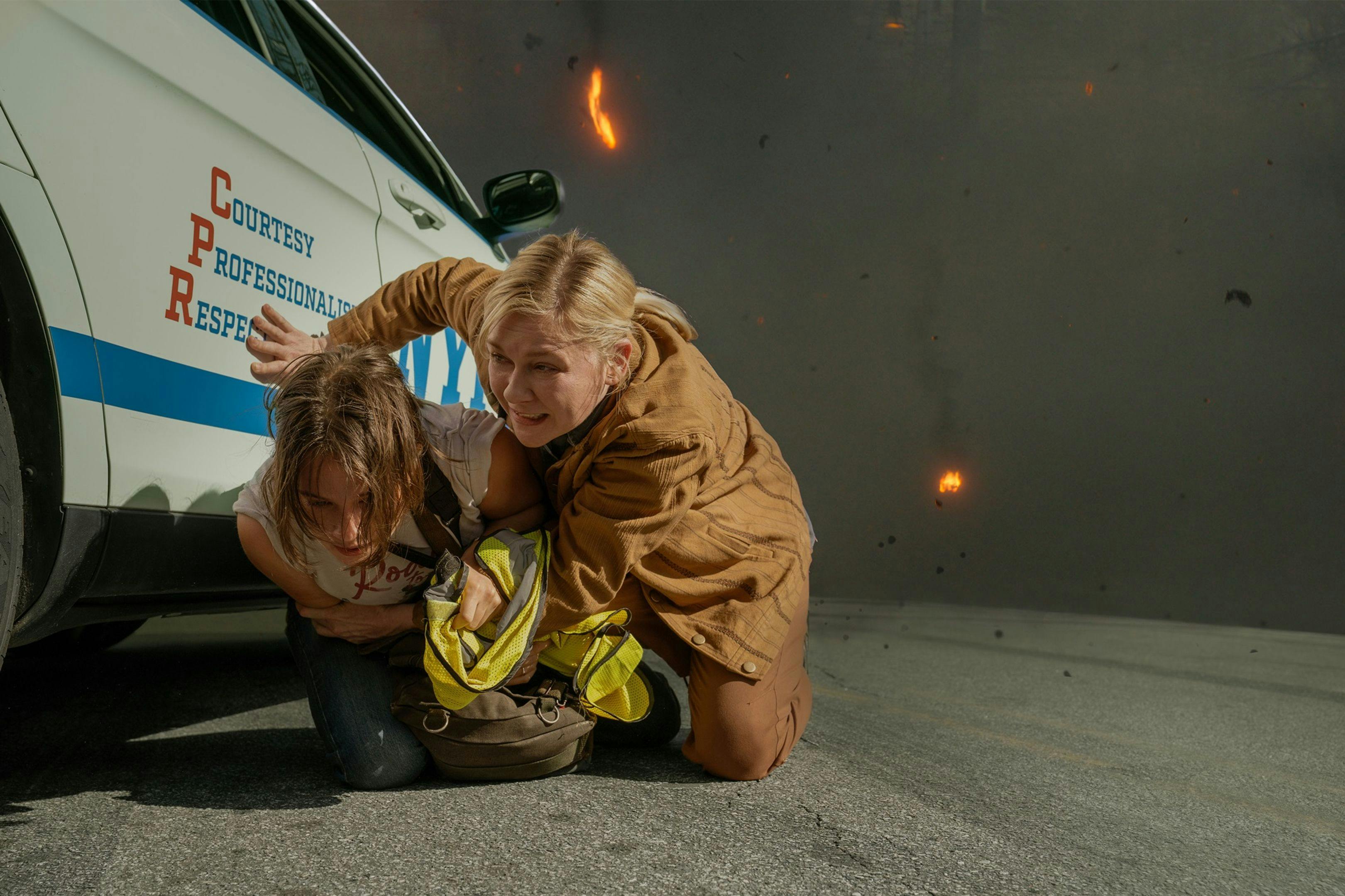 Kirsten Dunst y Cailee Spaeny se protegen de una explosión en un fotograma promocional de 'Civil War'