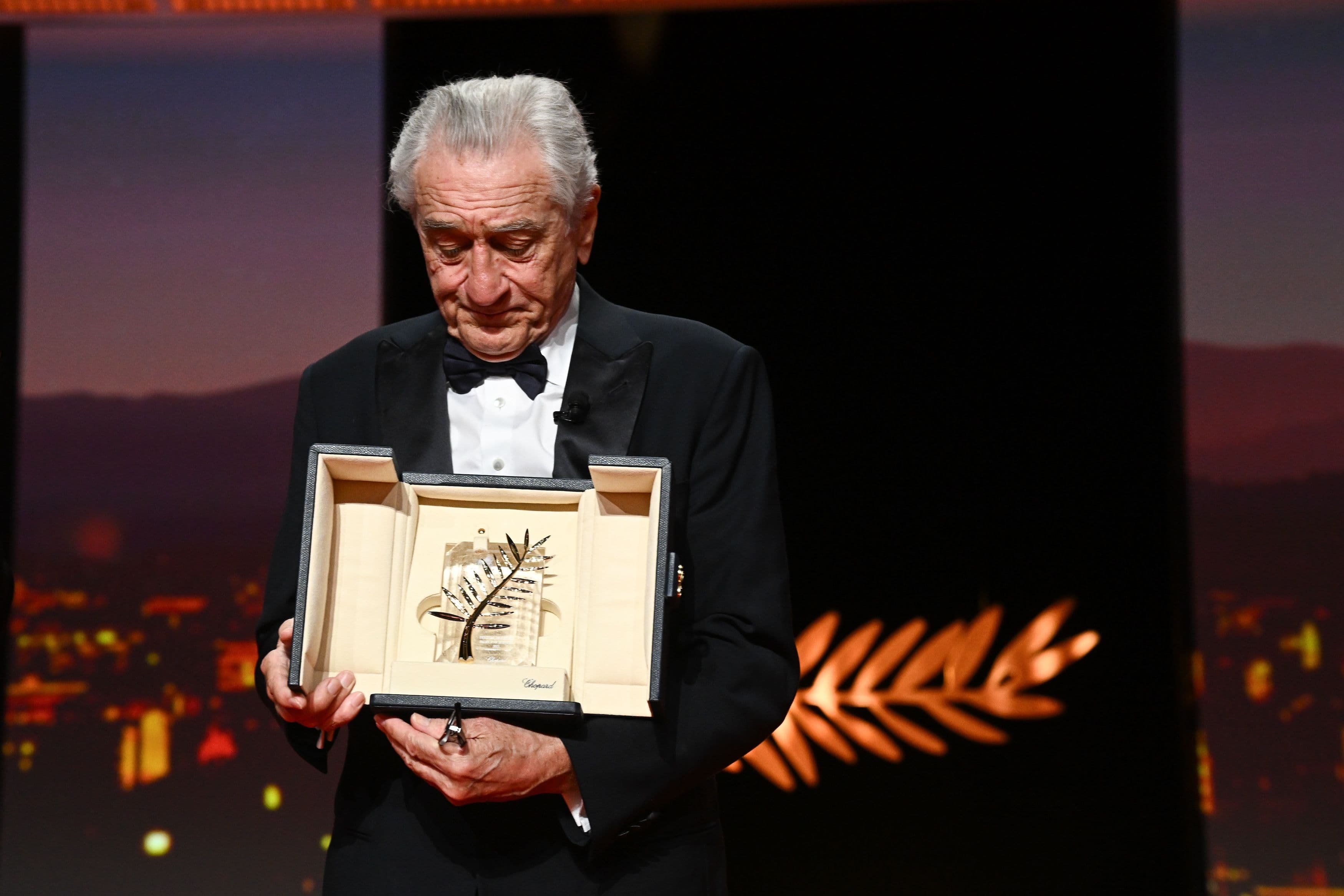 El actor Robert de Niro mira su Palma de Oro honorífica durante la ceremonia de apertura del Festival de Cannes 2025
