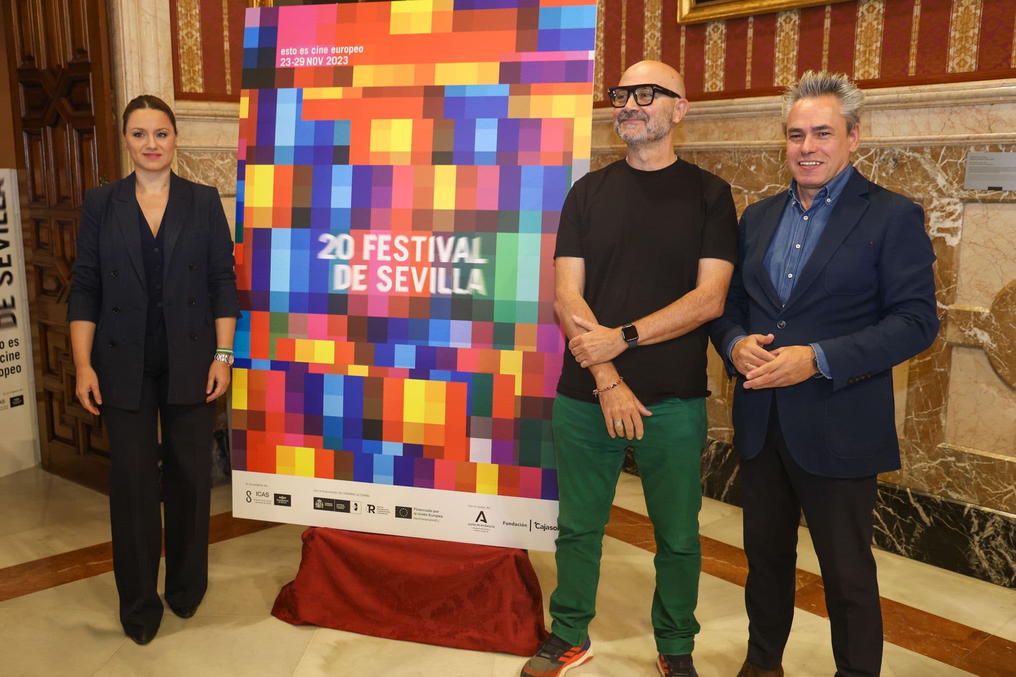 El coordinador del Festival de Sevilla, Manuel Cristóbal (d), posa junto al cartel de la edición número 20