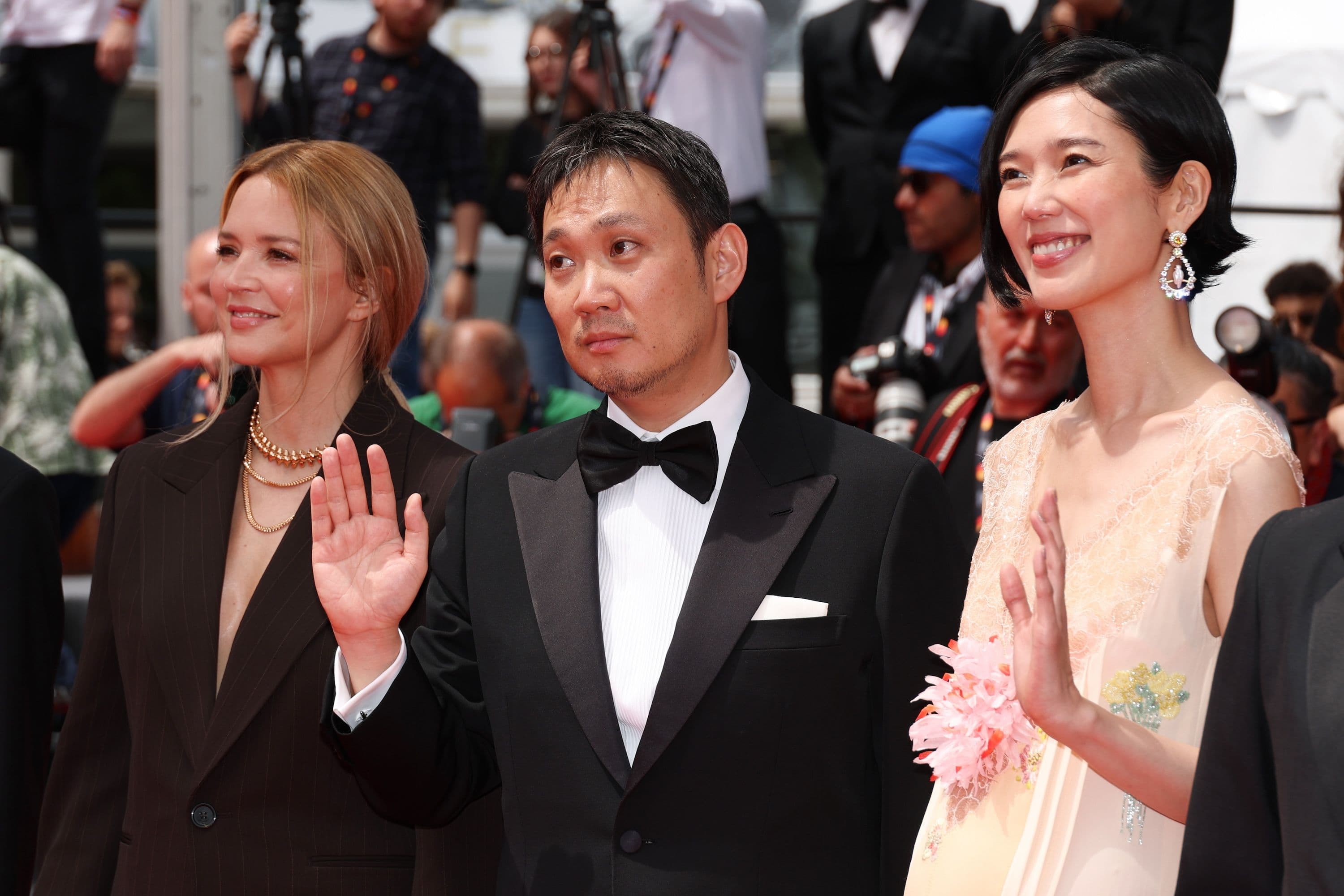 El director Ryusuke Hamaguchi saluda, junto a las actrices Virginie Efira y Tao Okamoto, en la alfombra roja de 'All of a Sudden' durante el Festival de Cannes 2026