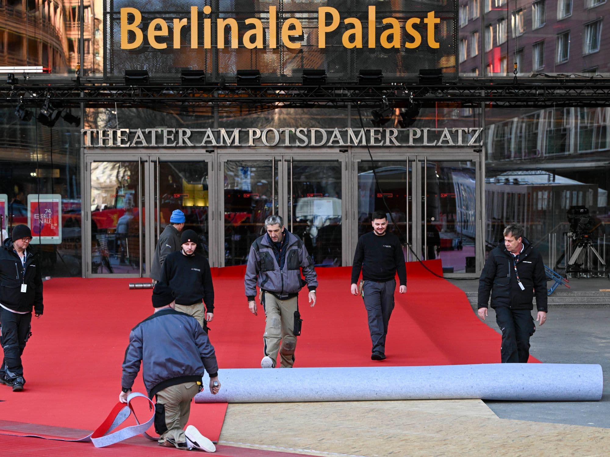 Varios trabajadores del Festival de Berlín despliegan la alfombra roja de la edición de 2024 ante el Berlinale Palast