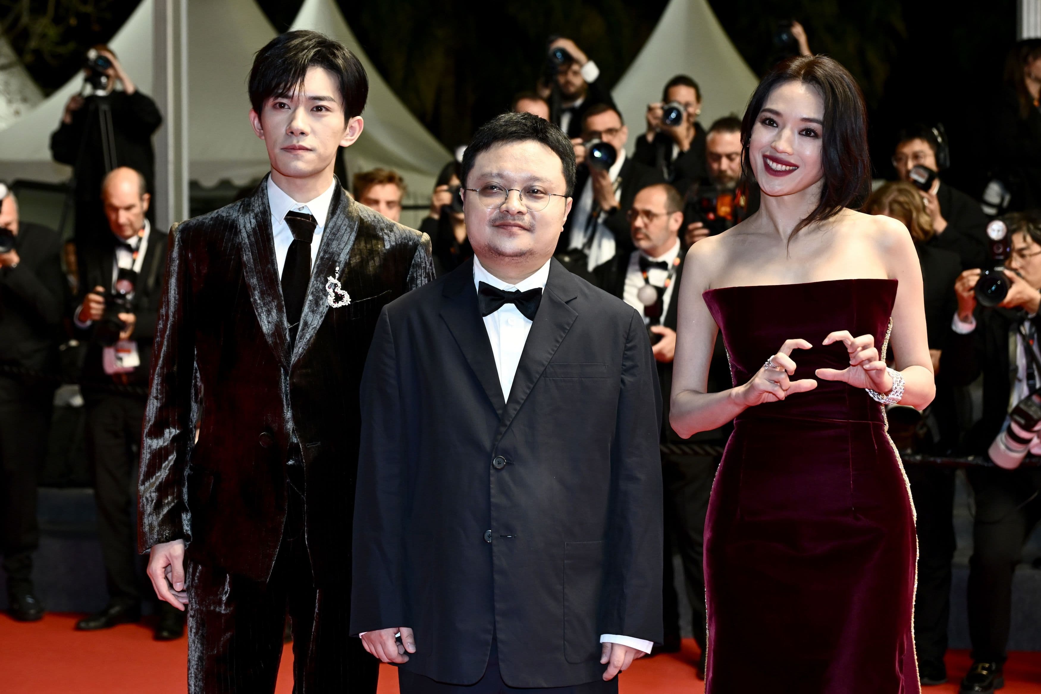 El director chino Bi Gan, rodeado por los actores Jackson Yee y Shu Qi en la alfombra roja de Cannes 2025
