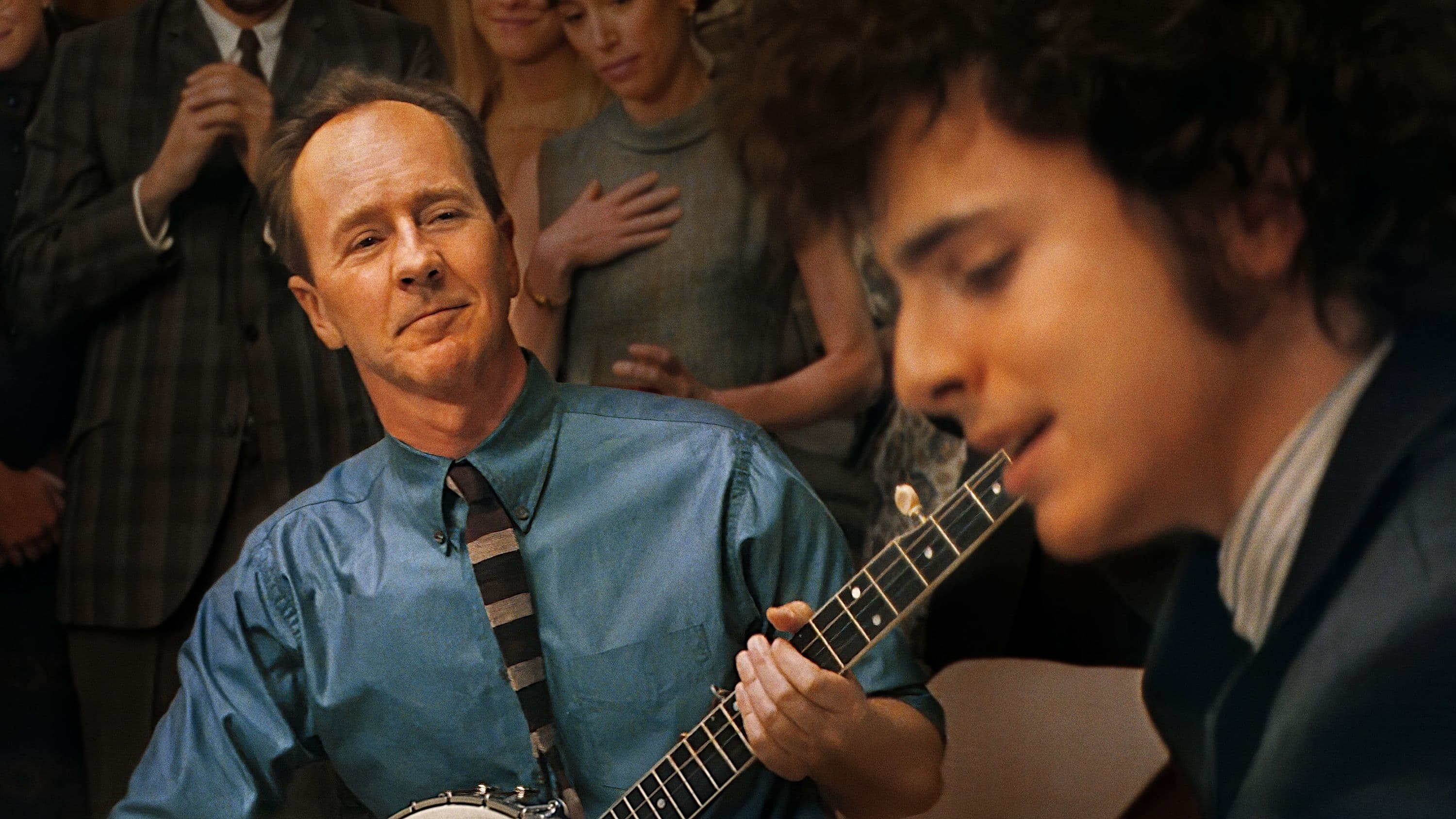 Edward Norton, caracterizado como Pete Seeger, escucha al personaje de Timothée Chalamet en un fotograma promocional de 'A complete unknown'