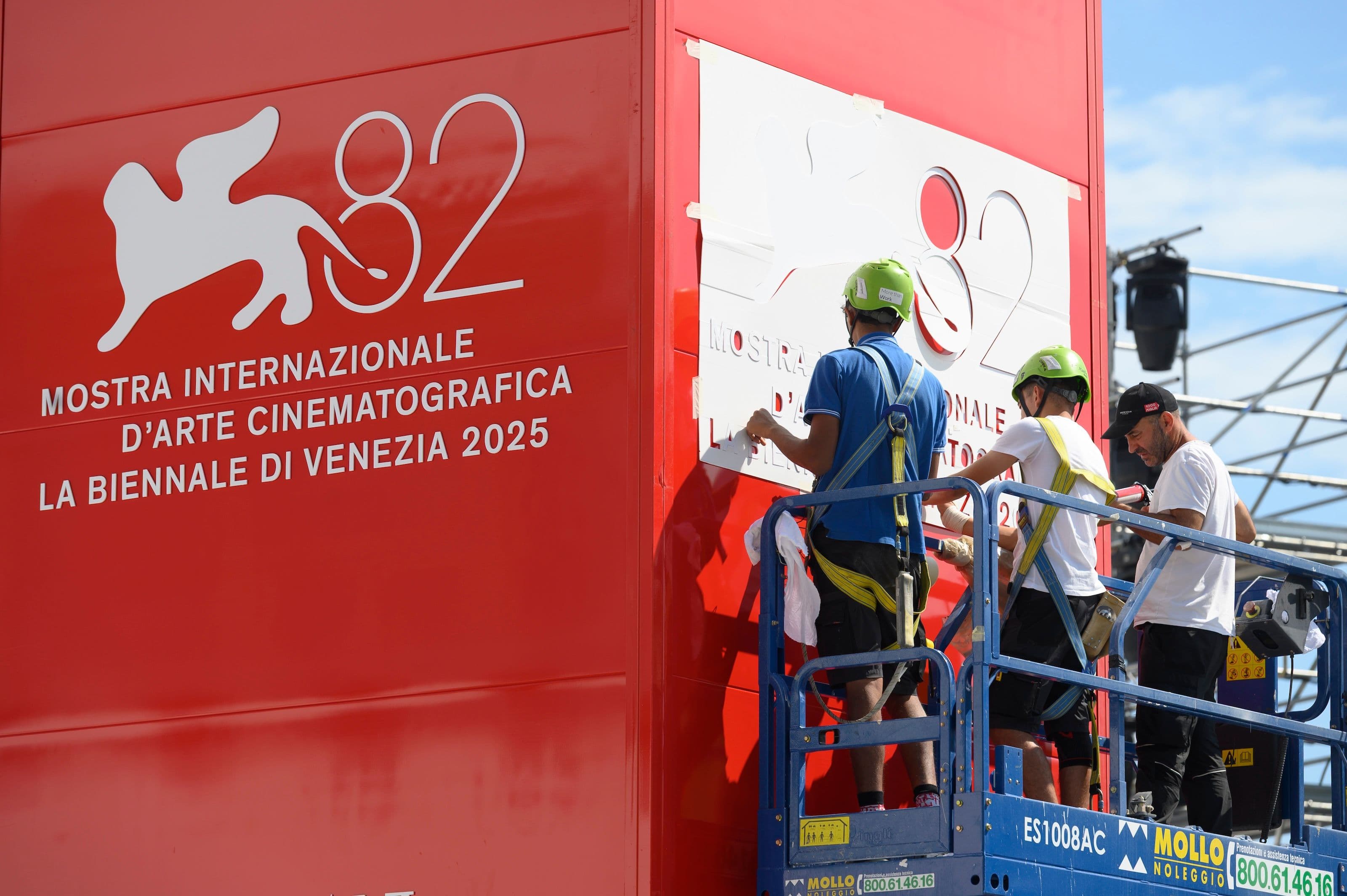 Un grupo de operarios instala el logo de la Mostra de Venecia 2025 a pocas horas del arranque del festival