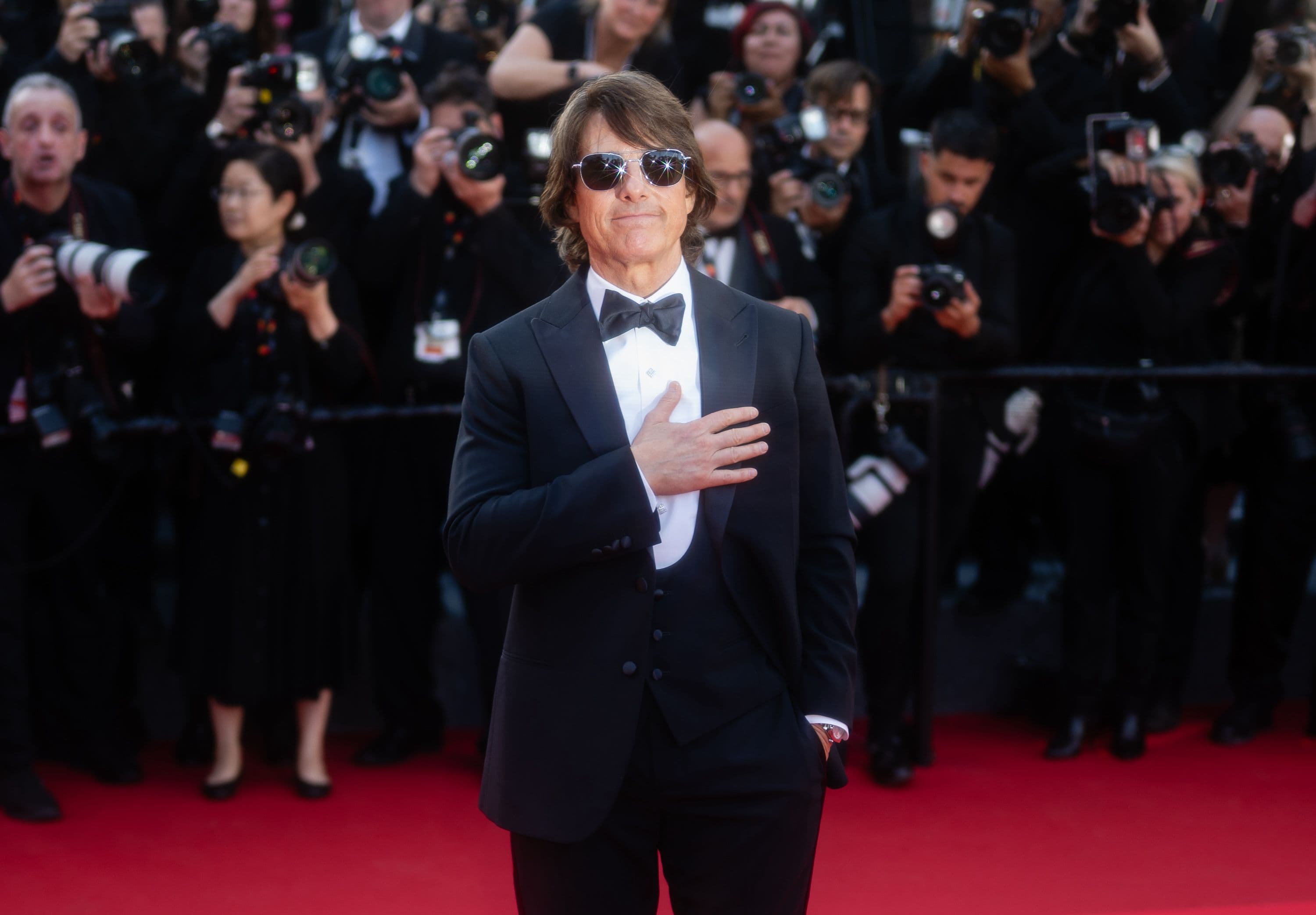 El actor Tom Cruise saluda a los fotógrafos en la alfombra roja de 'Misión imposible: Sentencia final' en Cannes 2025